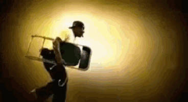 a man in a hat is carrying a chair in a dark room
