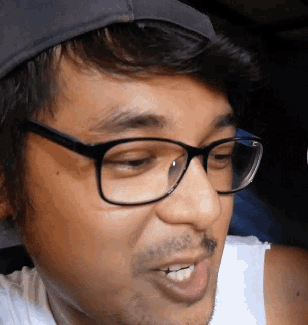 a man wearing glasses and a hat is smiling