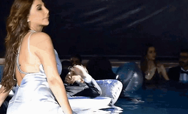 a woman in a blue dress is sitting in a swimming pool