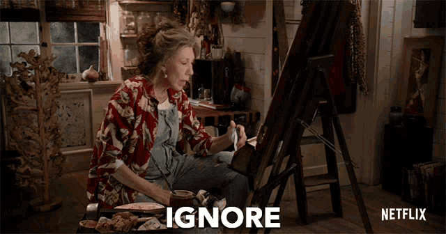 a woman sits in front of an easel with a netflix logo in the background