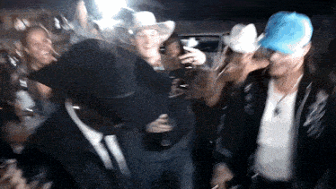a man in a cowboy hat is dancing in a crowd of people