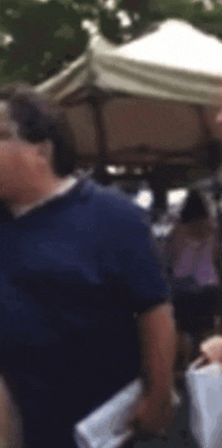 a blurry picture of a man in a blue shirt standing in front of a tent