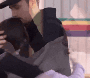 a man and a woman are hugging each other in front of a rainbow flag .