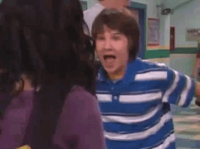 a boy in a blue and white striped shirt is making a face