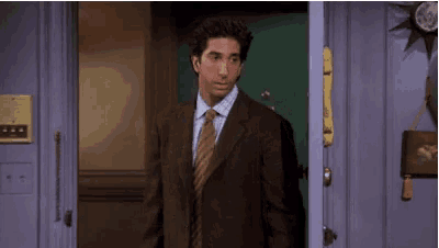 a man in a suit and tie is walking through a doorway .