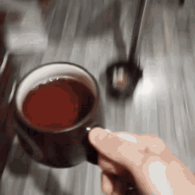 a person holding a cup of tea on a table