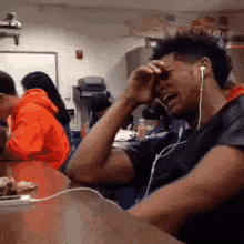 a man wearing ear buds is crying while sitting at a table