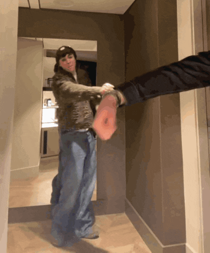 a person standing in a hallway with their hand on another person 's arm