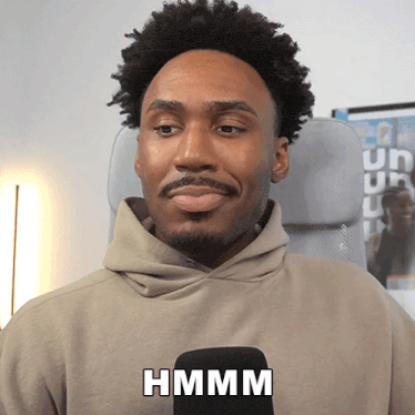 a man wearing a hoodie with the word hmm on the front