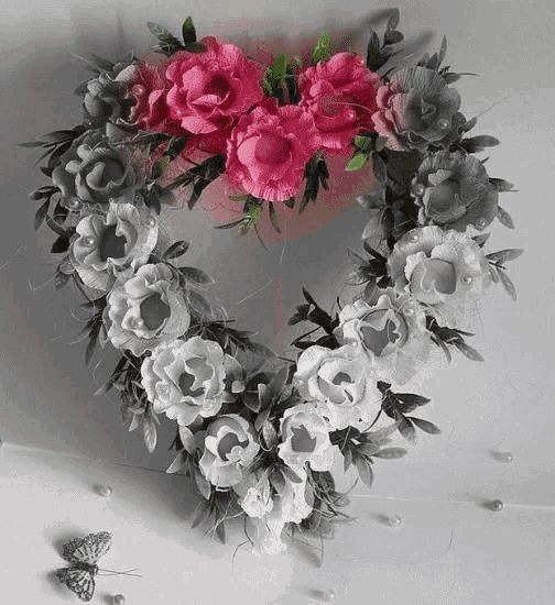a heart shaped wreath made of pink , white , and gray flowers