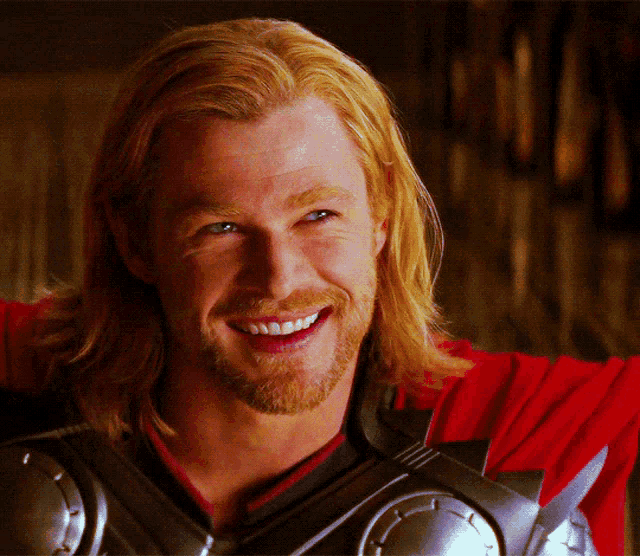 a man with long blonde hair and a beard is smiling for the camera