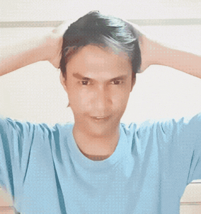 a man wearing a light blue shirt is holding his hands to his ears