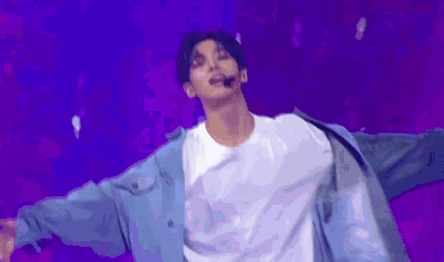 a man in a white shirt and blue jacket is dancing on a stage .