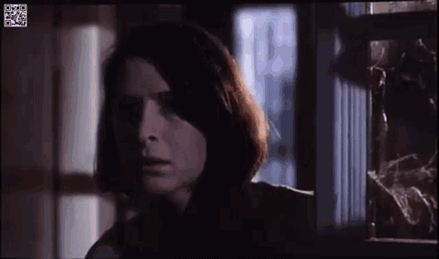 a close up of a woman 's face in a dark room looking out a window .