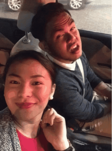 a man and a woman are sitting in a car and the woman is smiling