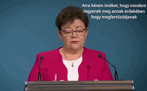 a woman with glasses and a cross necklace stands at a podium with the words arra kérem önöket hogy mindent