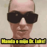 a man wearing sunglasses with the words manda o mijo dr. luke written on it .
