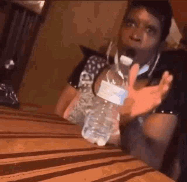 a woman is holding a bottle of water on a table .