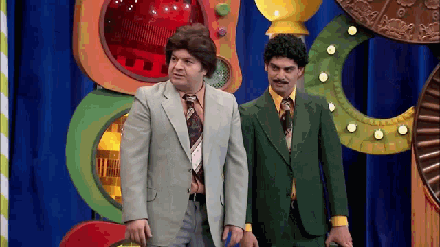 two men in suits are standing next to each other in front of a colorful background