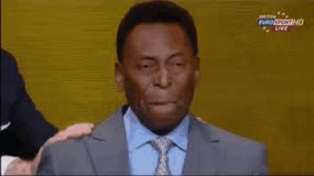 a man in a suit and tie is making a funny face while being hugged by another man .