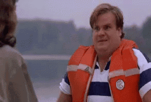 a man wearing a life jacket and a striped shirt is talking to a woman .