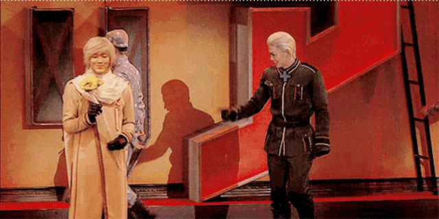 a man in a military uniform is standing next to a woman in a yellow dress on a stage .