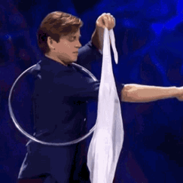 a man in a blue shirt is holding a white cloth and a hoop around his waist .