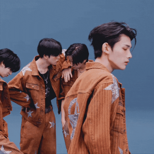 a group of young men are dancing together and one of them is wearing a brown jacket with silver stars on it