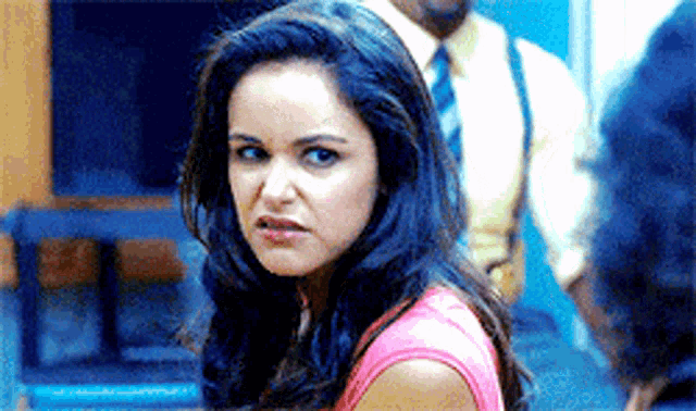 a woman in a pink shirt is making a funny face while standing in a room .