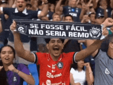 a man in a red shirt holds up a scarf that says se fosse facil
