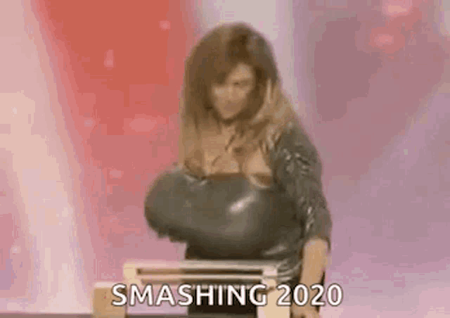 a woman is standing in front of a laptop computer and smashing 2020 .