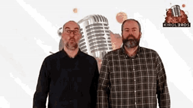 two men standing next to each other with a microphone in the background .