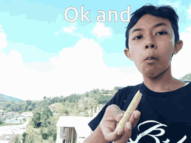 a boy in a black shirt is holding a yellow object in his hand with the words ok and above him