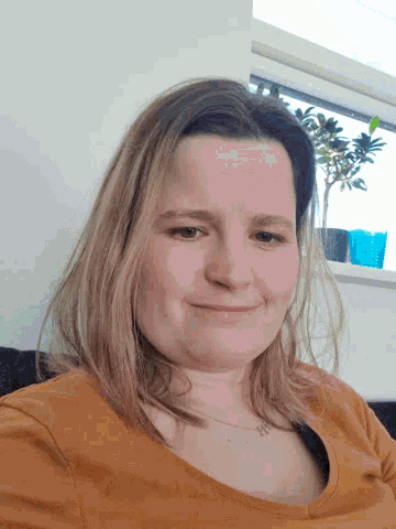 a woman in an orange shirt is smiling and looking down