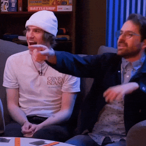 a man pointing at another man wearing a coney island t-shirt