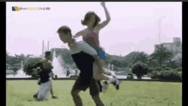 a man is carrying a woman on his shoulders in a field