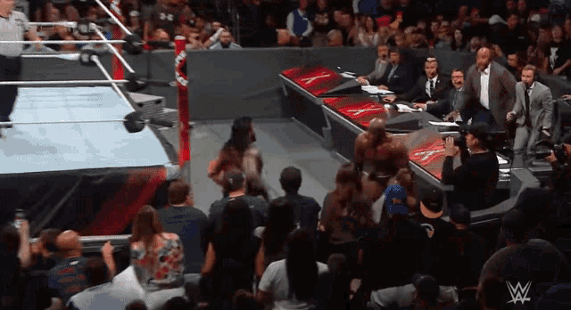 a crowd of people watching a wrestling match with a w logo