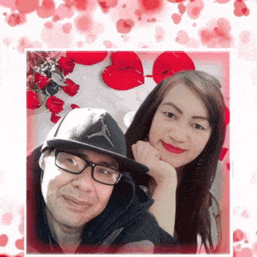 a man and a woman are posing for a picture in front of red hearts and roses