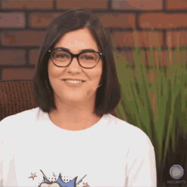 a woman wearing glasses and a t-shirt that says record tv smiles