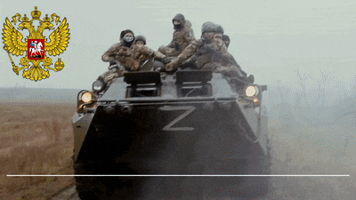 a group of soldiers are riding on top of a military vehicle with the letter z on it