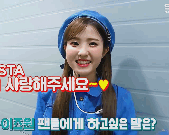 a woman wearing a blue hat and a blue jacket is smiling in a video with korean writing