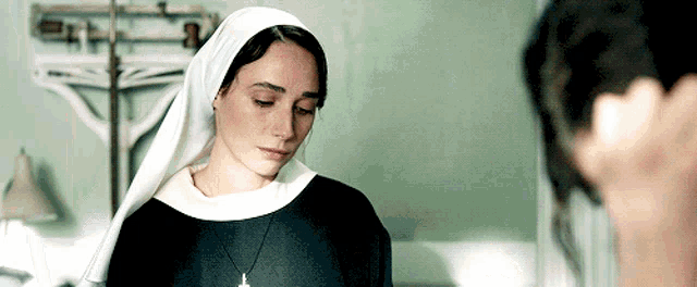 a nun with a cross around her neck looks at another woman