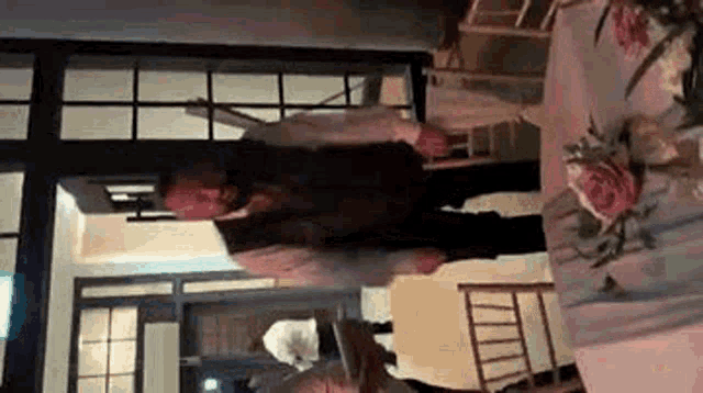 a man is standing in a room next to a table and chairs .
