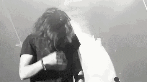 a black and white photo of a woman covering her face with her hair while standing next to a man .