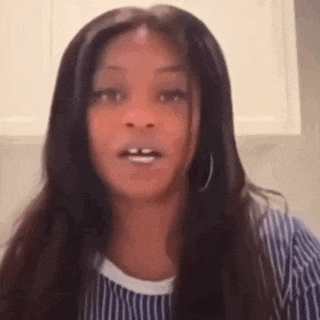a woman with long hair and hoop earrings is wearing a striped shirt and making a funny face .
