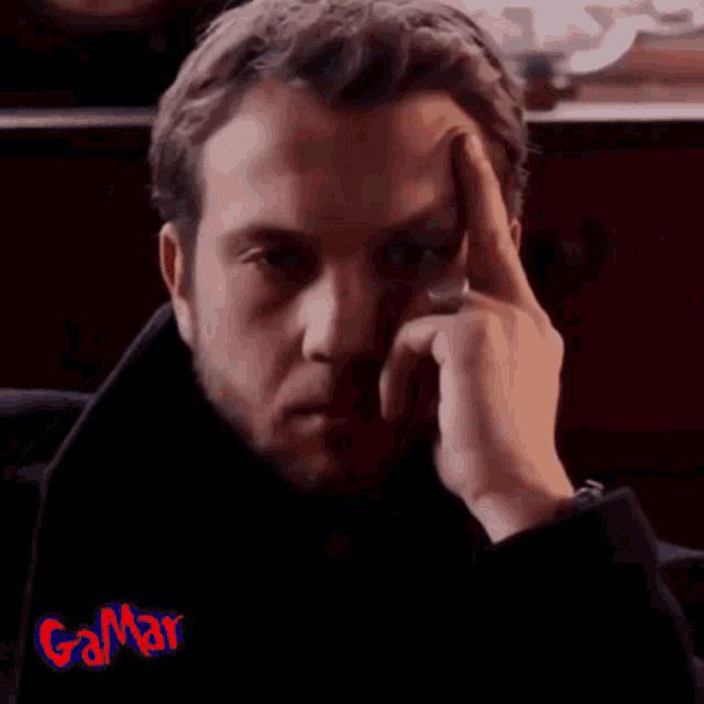 a man with a ring on his finger has his hand on his forehead .