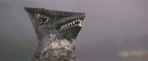 a close up of a dinosaur 's head with its mouth open and a tooth sticking out .