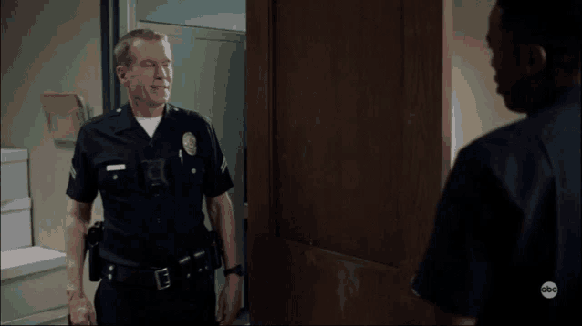 a man in a police uniform stands in front of a door with abc written on the bottom right corner