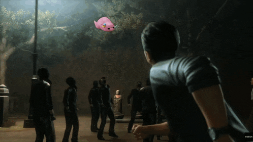 a man in a black shirt is standing in front of a group of people with a pink balloon flying in the air