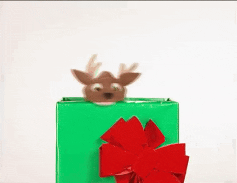 a stuffed reindeer is peeking out of a green christmas present .
